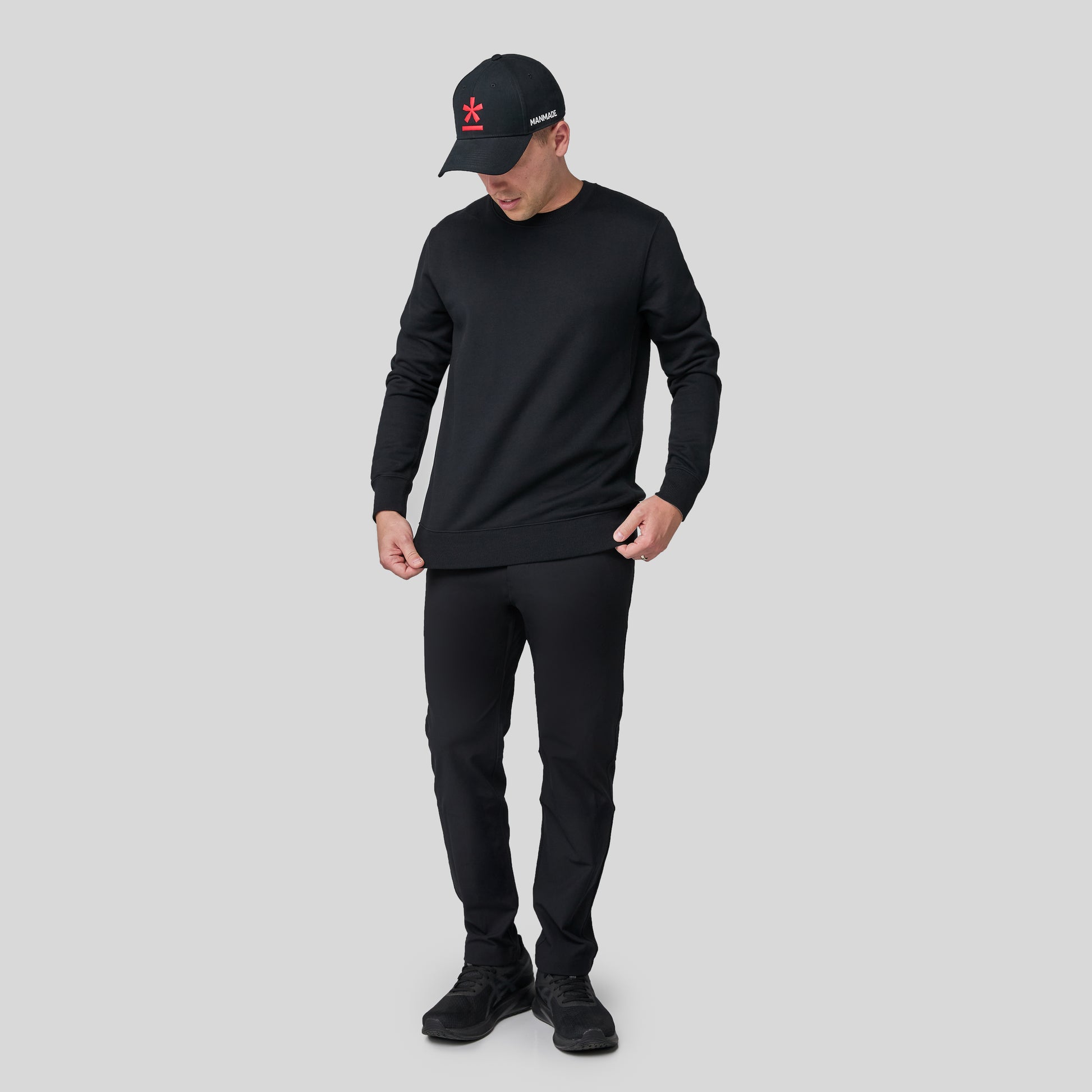 Full-body shot of Berto wearing the black swartshirt on a light gray background