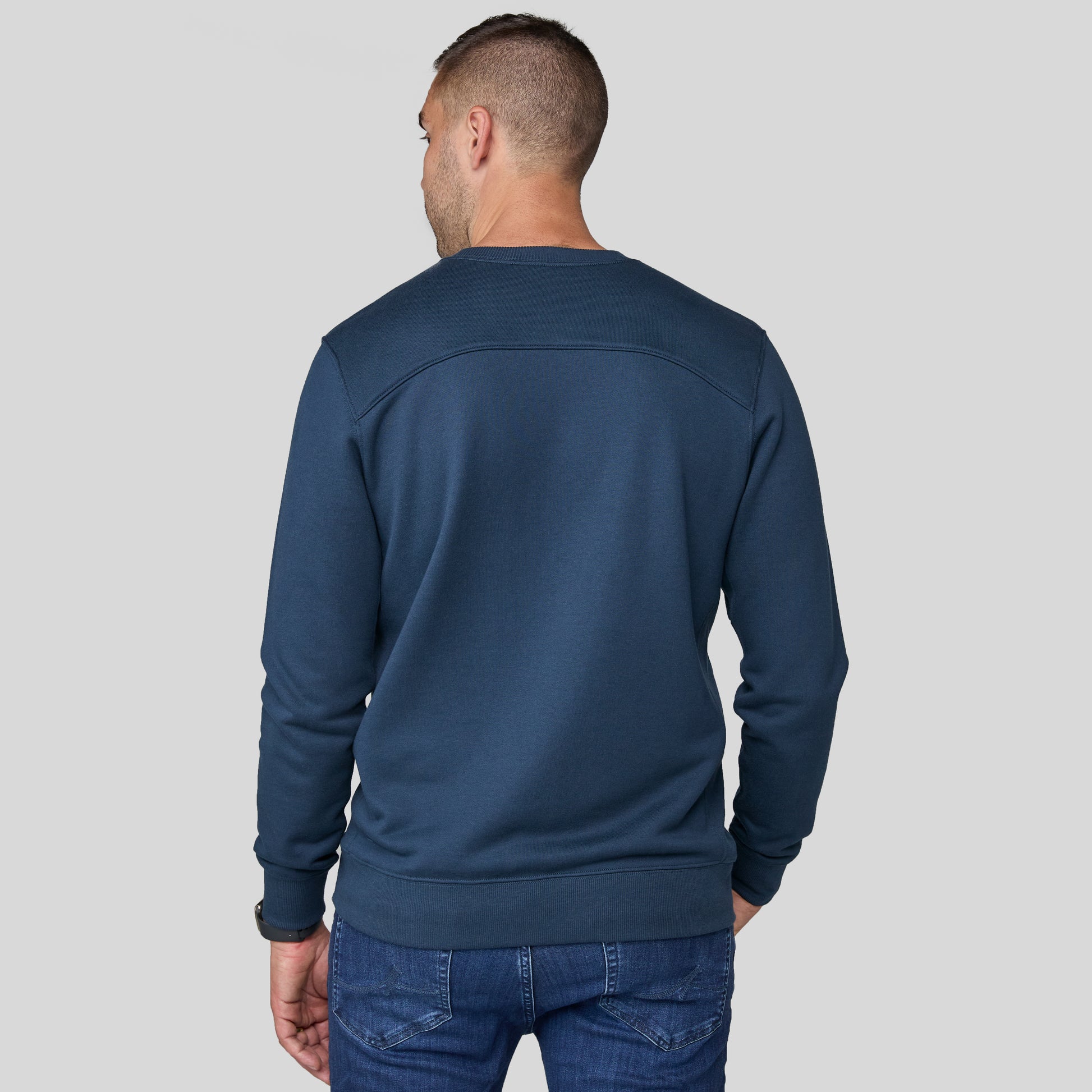 Phil wearing the blue sweater on a gray background