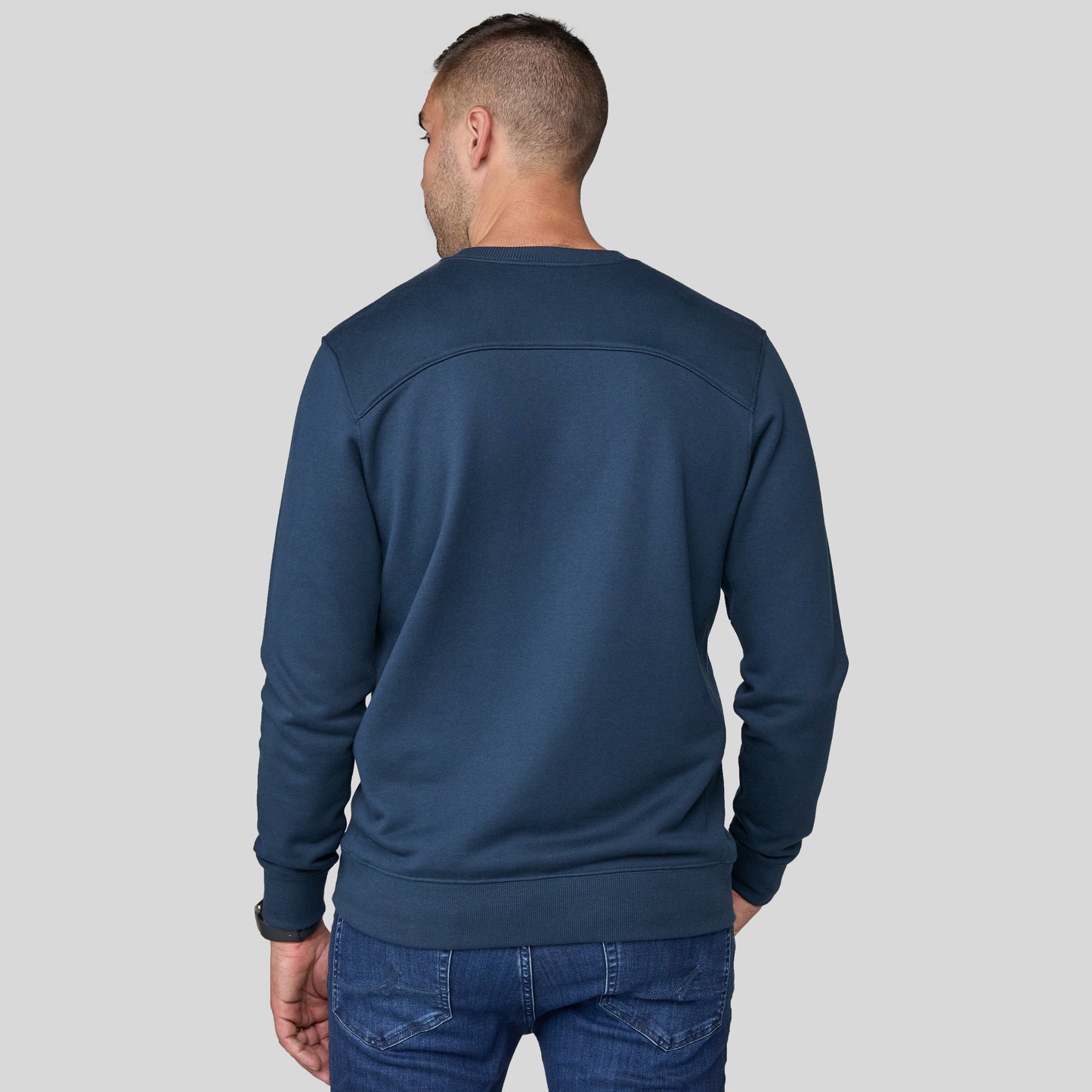 Phil wearing the blue sweater on a gray background